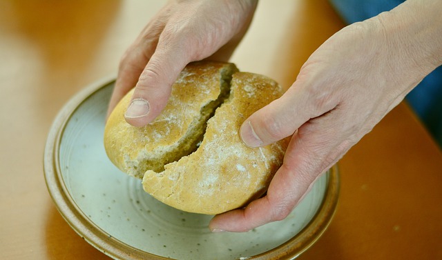 Brood wordt gebroken tijdens de jaarlijkse buurtmaaltijd op het Dorpsplein